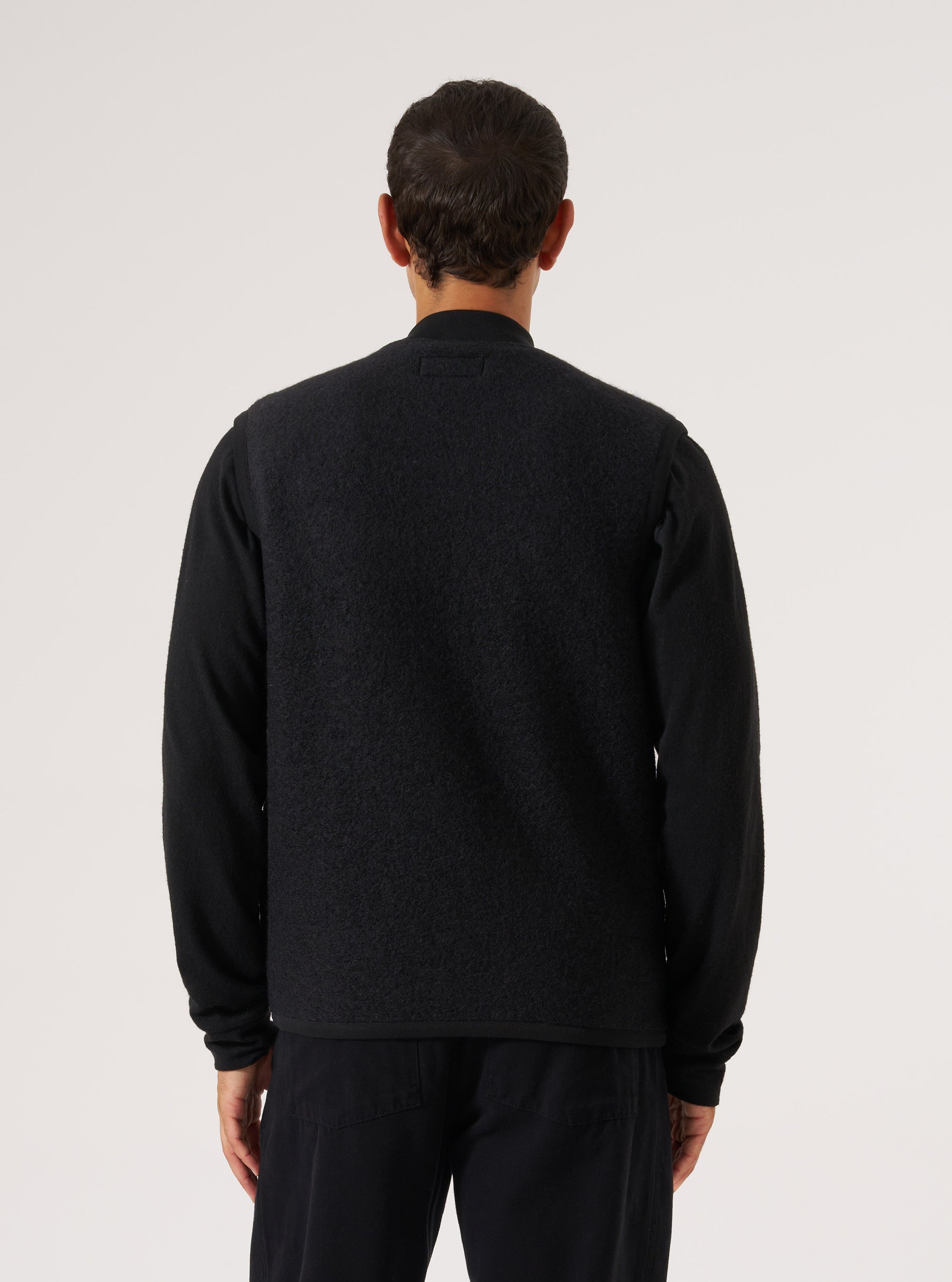 Back view of a model wearing a Black Wool Fleece Zip Waistcoat. The garment is displayed against a plain white background.