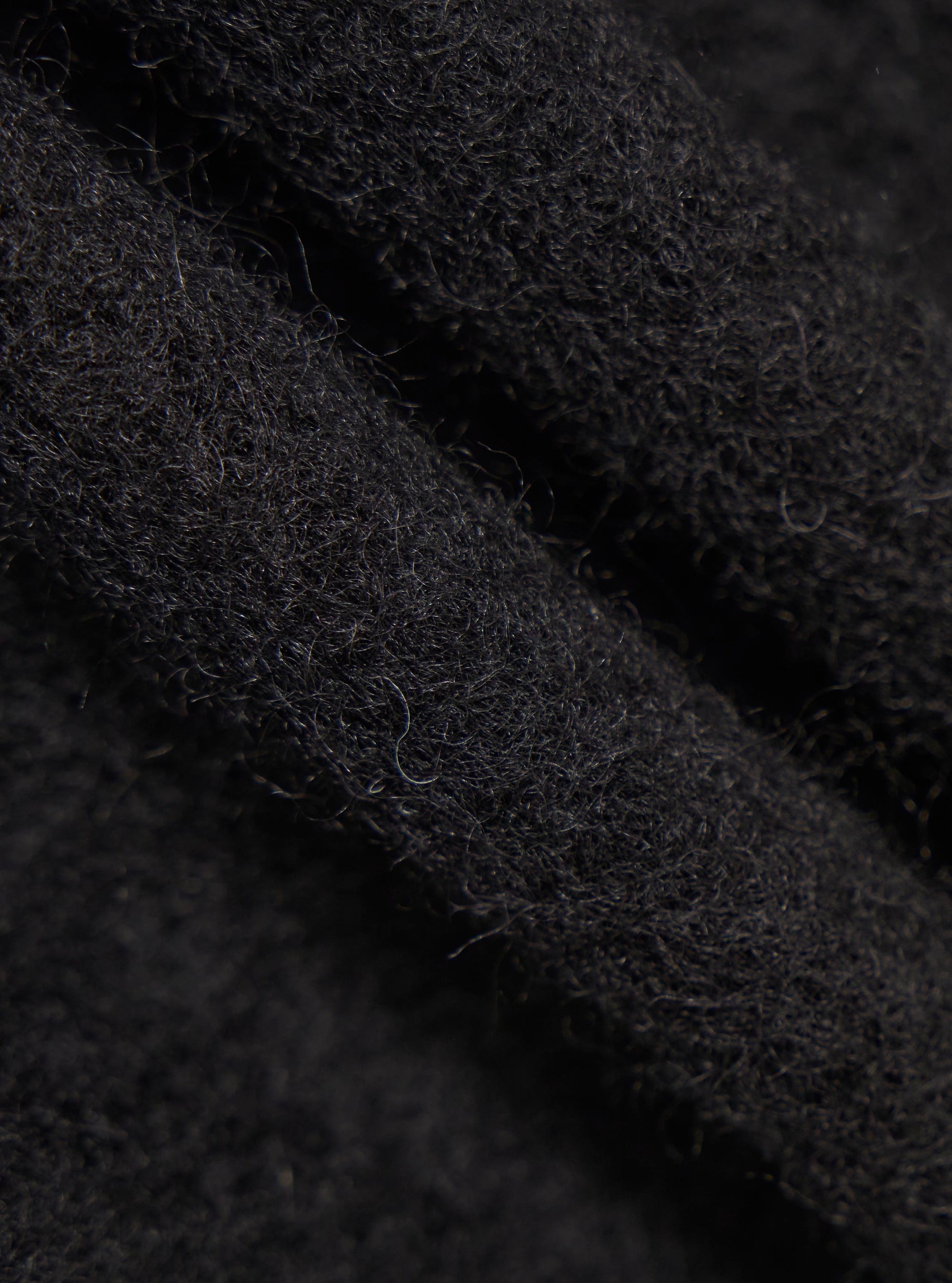 Close-up of the Black Wool Fleece Zip Waistcoat. The image shows the texture of the black wool fleece material.