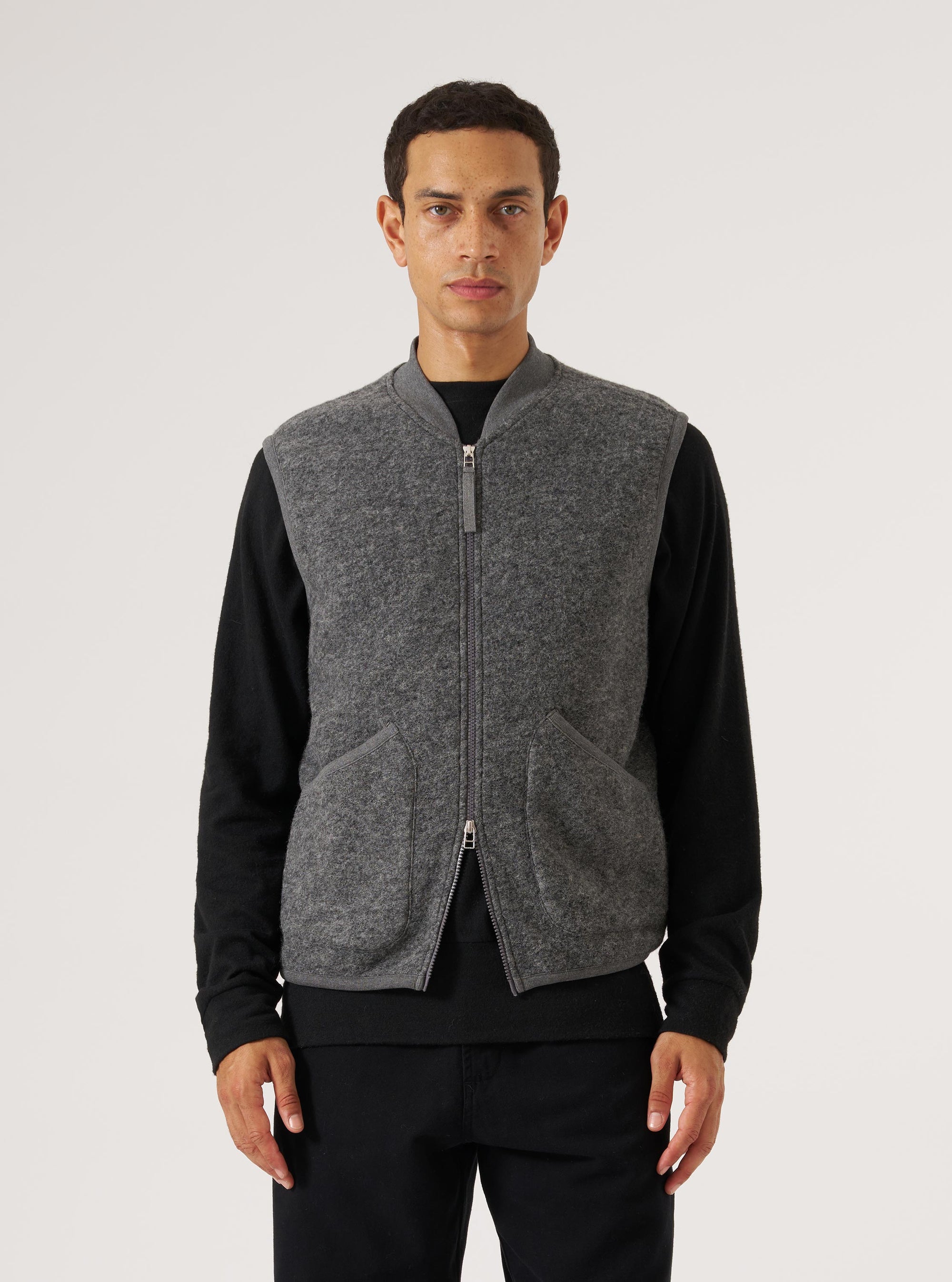A model wears a Grey Marl Wool Fleece Zip Waistcoat against a white background. The waistcoat is zipped up and has pockets.