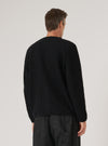 Back view of a man wearing a Black Wool Fleece Cardigan. The image is shot in a studio with a plain background. The cardigan has a relaxed fit.