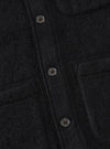 Close-up of the Black Wool Fleece Field Jacket showing the texture of the black wool fleece and button details. The jacket is neatly laid out on a flat surface.