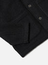 Close-up of the Black Wool Fleece Field Jacket on a white surface. Shows the texture, pockets, buttons, and construction details.