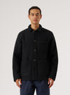 A man stands against a white backdrop, modeling a Black Wool Fleece Field Jacket. The jacket features a button-up design and patch pockets.