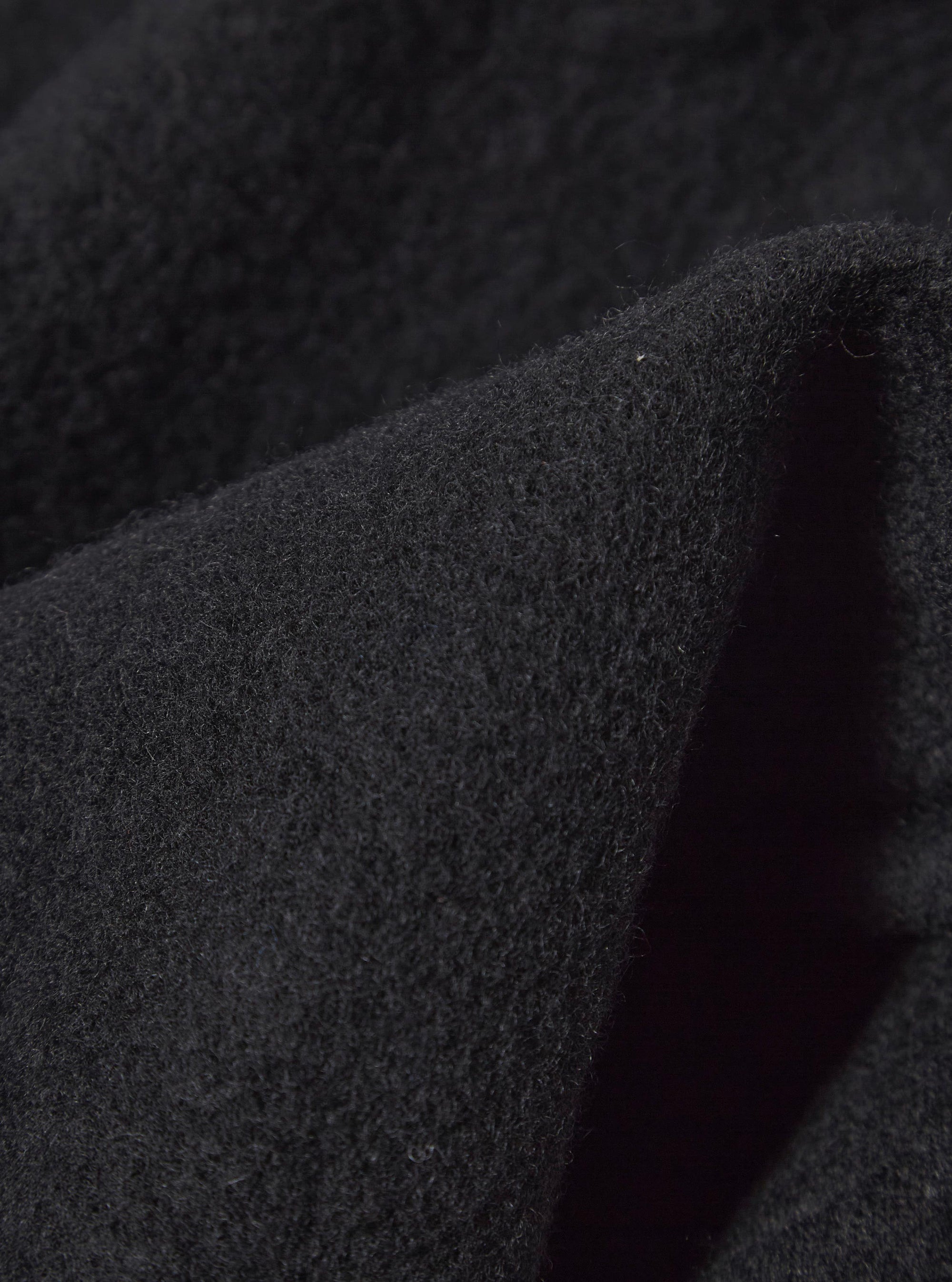 Close-up of the Black Wool Fleece Field Jacket, showing the texture and color of the wool fleece material. The jacket is displayed on a plain background.