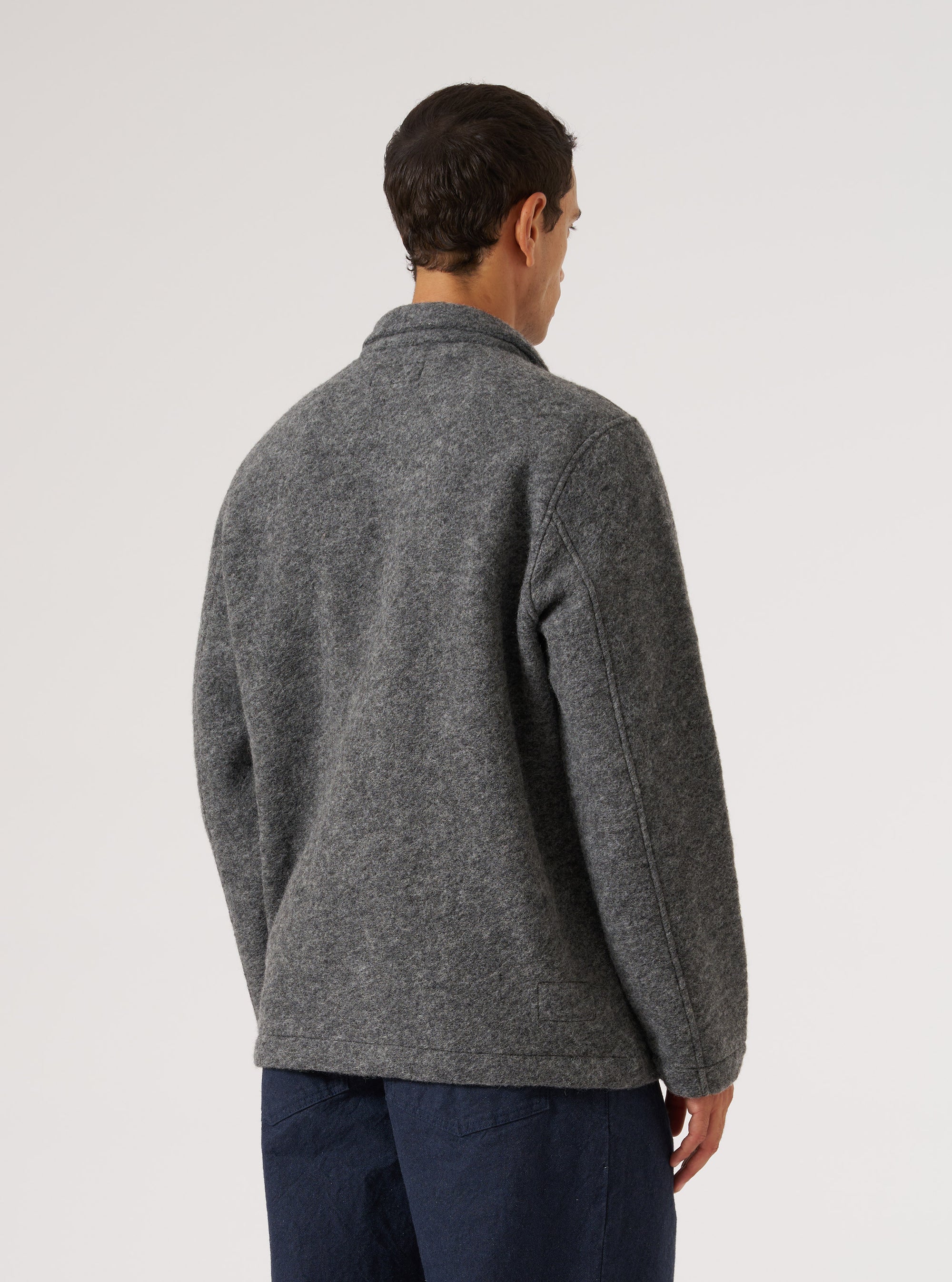 Back view of a man wearing a Grey Marl Wool Fleece Field Jacket. The jacket is paired with dark blue trousers. The background is a plain white studio backdrop.
