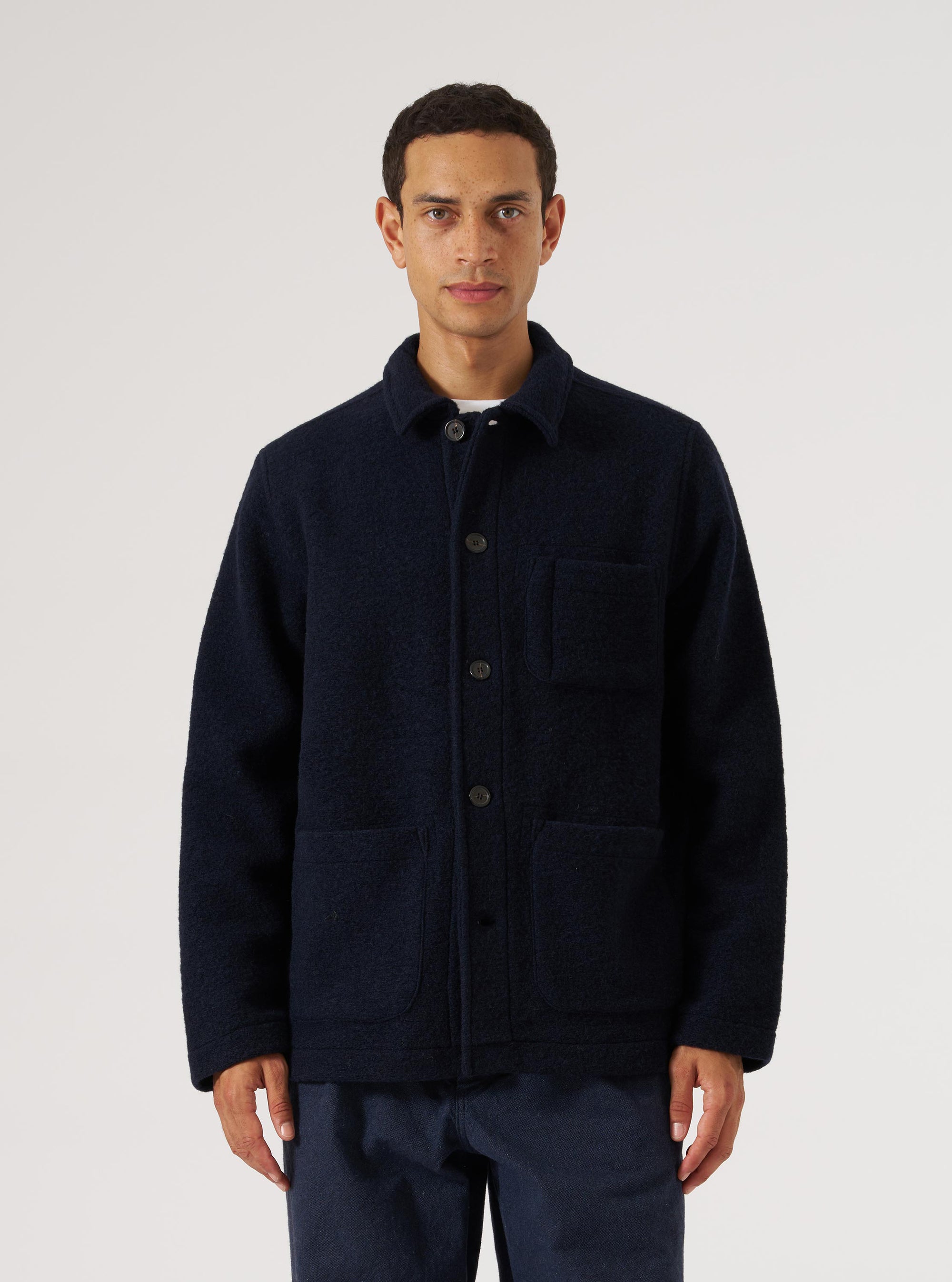 A man models the Navy Wool Fleece Field Jacket against a white backdrop. The jacket is a deep navy with a textured wool fleece finish and button-up closure.