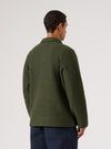 Back view of a man wearing the Olive Wool Fleece Field Jacket. The jacket is olive green and made of wool fleece. He is wearing dark blue pants. White background.