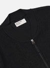 Close-up of a Black Wool Fleece Zip Bomber on a white background. The bomber has a ribbed collar and a silver zipper. The fabric is a textured wool fleece.