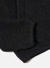 Close-up of the Black Wool Fleece Zip Bomber sleeve on a white background. The black wool fleece material is visible, along with the ribbed cuff.