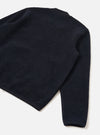 Navy wool fleece zip bomber laid flat on a white surface, shot from above at an angle showing the back and one sleeve. The textured fleece is trimmed with smooth navy grosgrain or woven binding at the crew neck, cuffs, and hem. A small silver zip pull is visible at the lower left hem.