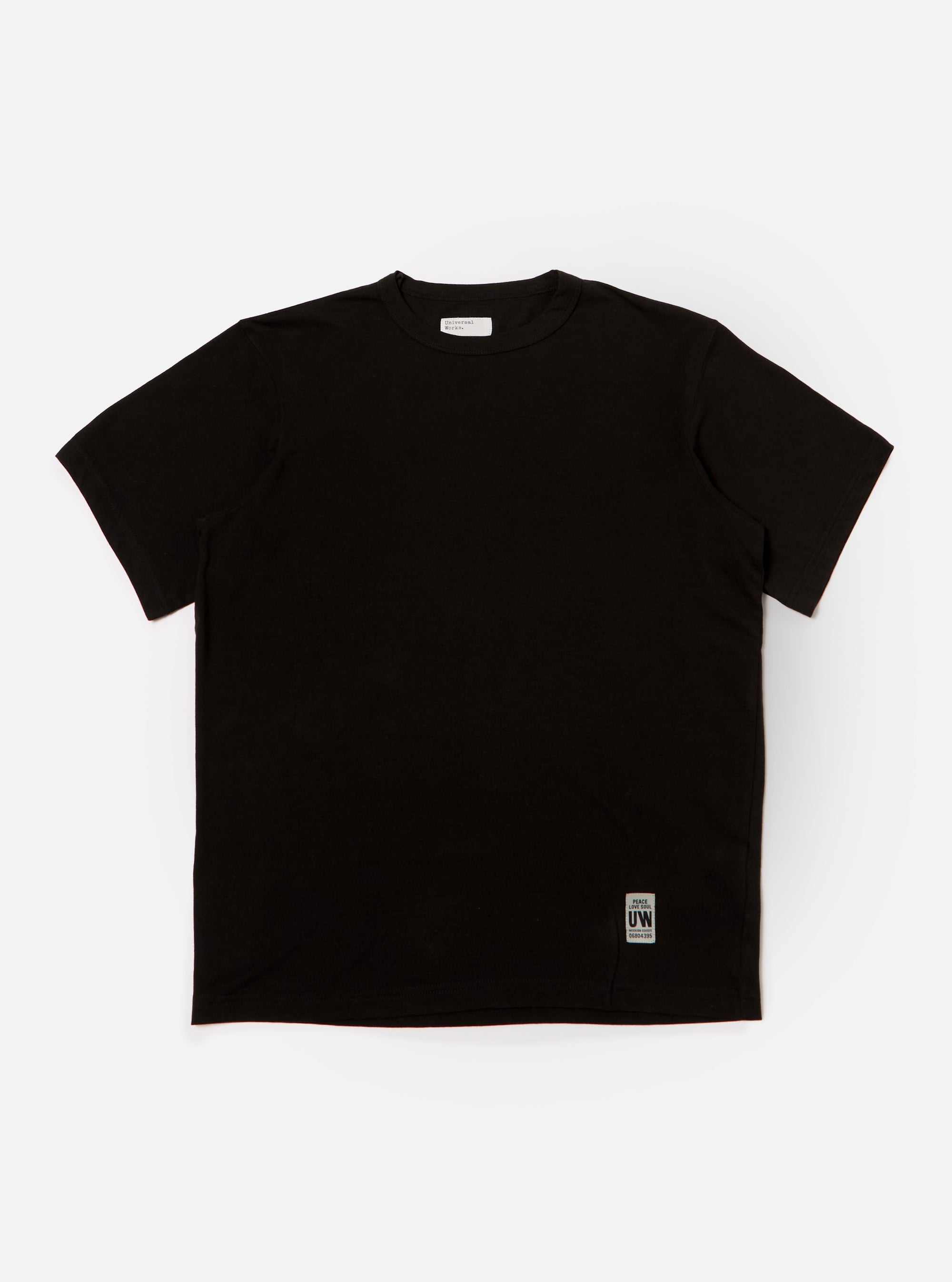 The Black Single Jersey Core Tee is displayed on a white background. The tee is a solid black color and has a relaxed fit.