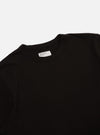Close-up of a Black Single Jersey Core Tee on a white background. The simple tee shows the collar and upper chest area.