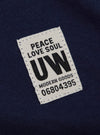 Close-up of the Navy Single Jersey Core Tee showing the fabric and a tag with "Peace Love Soul UW Modern Goods 06804395" on it.