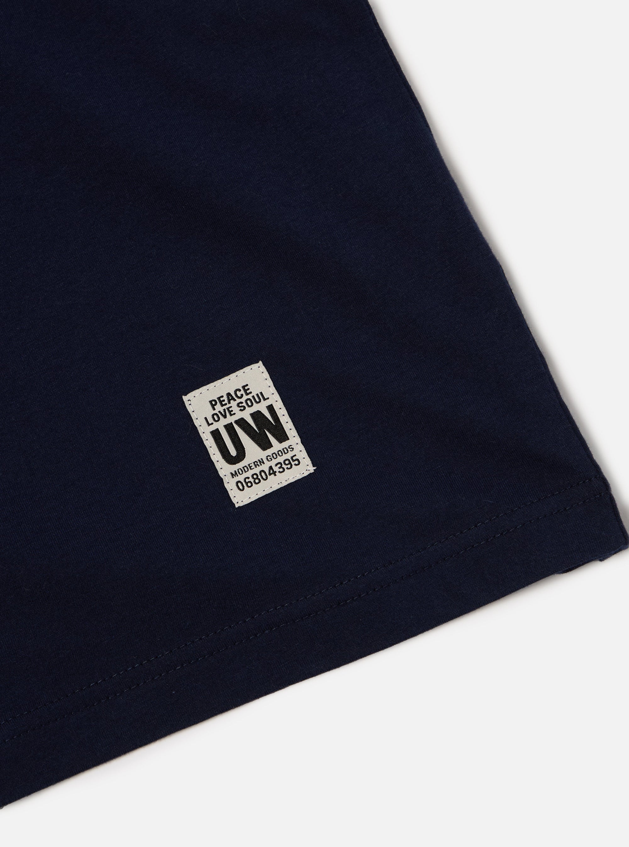 Close-up of the Navy Single Jersey Core Tee showing the fabric and label detail on a white background.