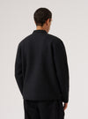 Back view of a model wearing a Black Wool Fleece Zip Liner Jacket against a white backdrop. The jacket is black wool fleece with a zip liner.