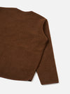 Close-up flat lay of a cacao brown wool fleece zip liner jacket on a light grey seamless backdrop. The shot captures the upper back, right shoulder seam and one full sleeve. The boiled wool fleece has a lightly textured, brushed surface. A narrow bound hem edge is visible at the sleeve and bottom.