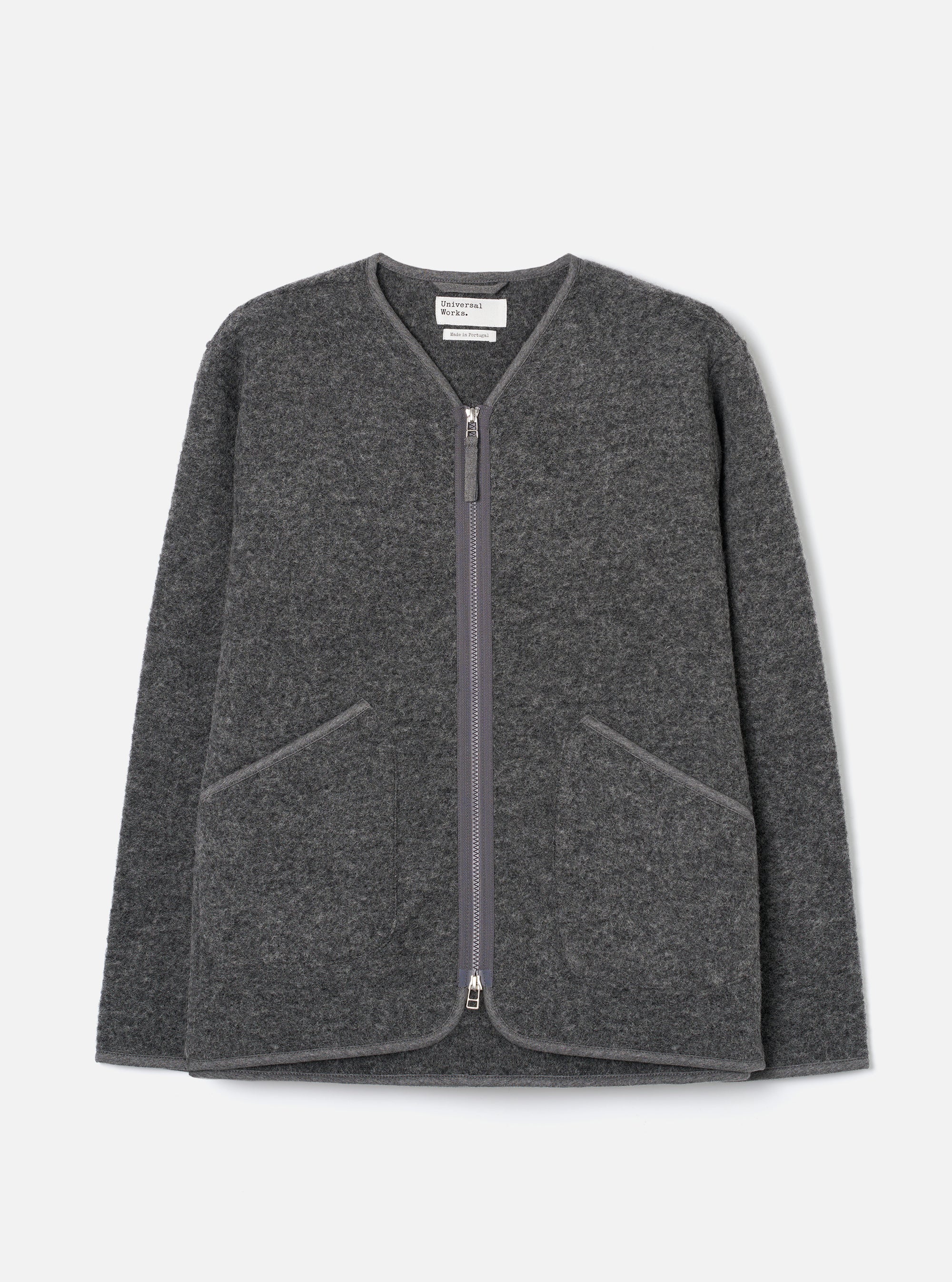 Grey marl wool fleece zip liner jacket, flat lay on a light grey seamless backdrop. Collarless V-neckline with tonal bound edges running down the full-length centre-front zip, which has silver metal pulls at top and bottom. Two large angled welt pockets at the lower front with matching bound trim. Textured boiled wool fleece fabric throughout.