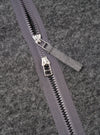 Close-up detail of the grey marl wool fleece zip liner jacket showing a two-way centre-front zip with two silver metal sliders and a fabric pull tab in matching grey. The zip tape is dark grey with black plastic teeth. The brushed wool fleece fabric texture is visible across the background.
