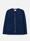 Indigo wool fleece zip liner jacket laid flat on a light grey seamless backdrop. Collarless V-neckline with navy binding trim, full-length silver zip, and two large patch pockets with matching bound edges. Textured boiled wool fleece fabric throughout. Universal Works woven label visible at the neck.