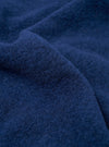 Close-up of the indigo wool fleece fabric used in the zip liner jacket. The boiled wool texture is dense and lightly brushed, with short curling fibres creating a soft, napped surface. The deep navy-indigo tone shows subtle variation across the draped folds of the cloth.