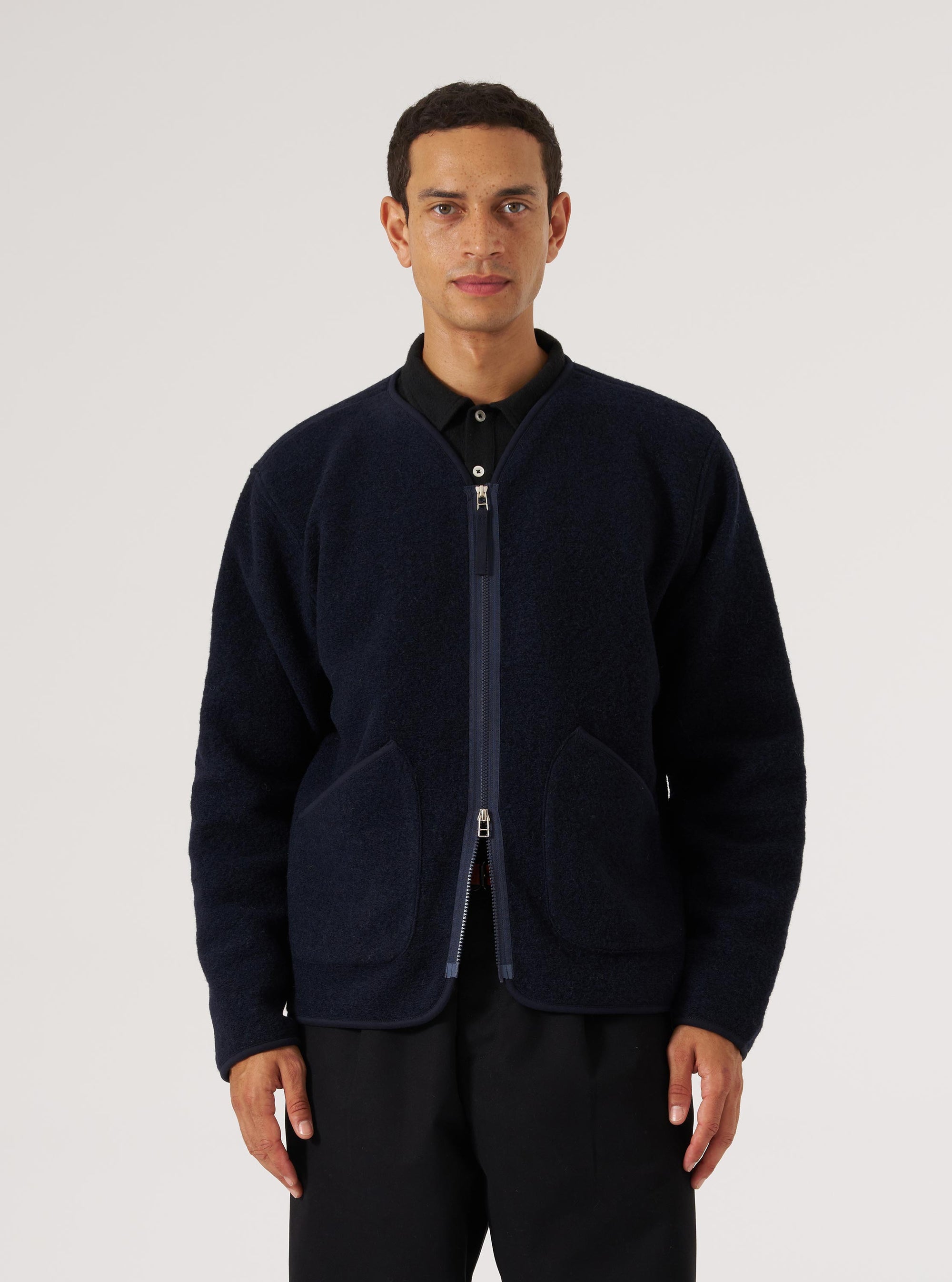 A model wears a Navy Wool Fleece Zip Liner Jacket in a studio shot against a white backdrop. The jacket is navy with a zip front and patch pockets.