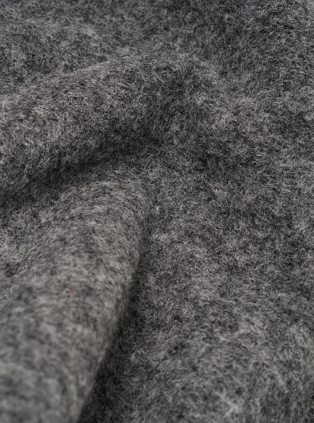 Close-up of the grey marl wool fleece fabric on the Uniform Jacket, showing the dense, brushed texture with fine fibres and a soft, chunky pile. Folds and curves in the material highlight the fabric's depth and volume. No background visible.
