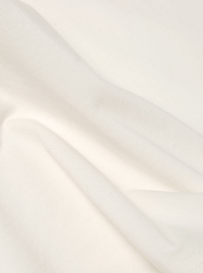 Close-up of the Ecru Single Jersey Core Tee fabric. Soft, off-white cotton with subtle folds. Studio shot on a plain background.