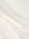 Close-up of the Ecru Single Jersey Core Tee fabric. Soft, off-white cotton with subtle folds. Studio shot on a plain background.