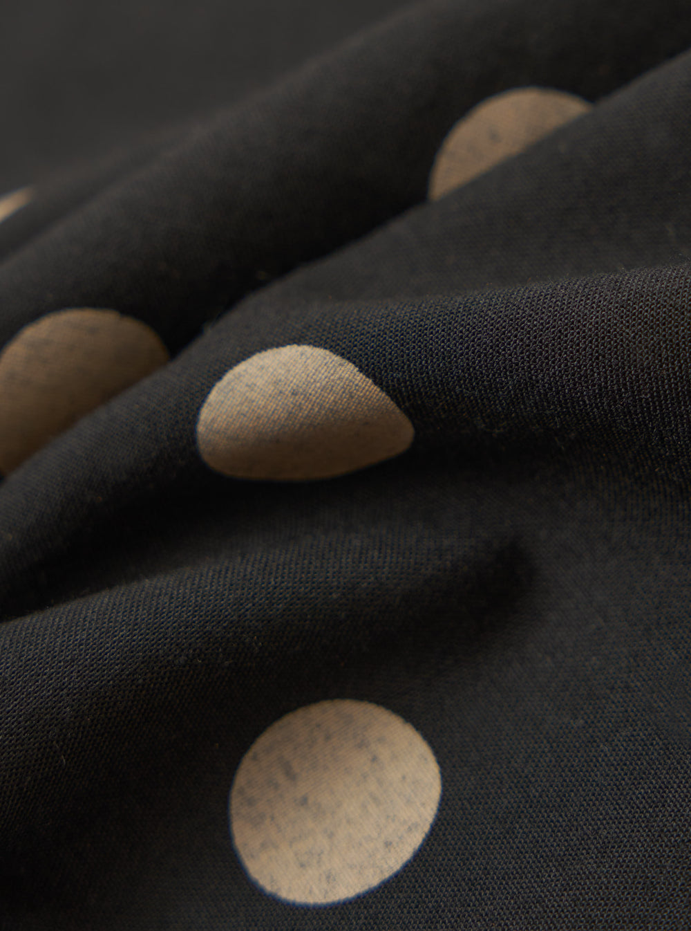 Close-up of the Black Bold Dot Print Rayon Scout Scarf. The black rayon fabric features large tan polka dots. The scarf is draped to show the texture and pattern.