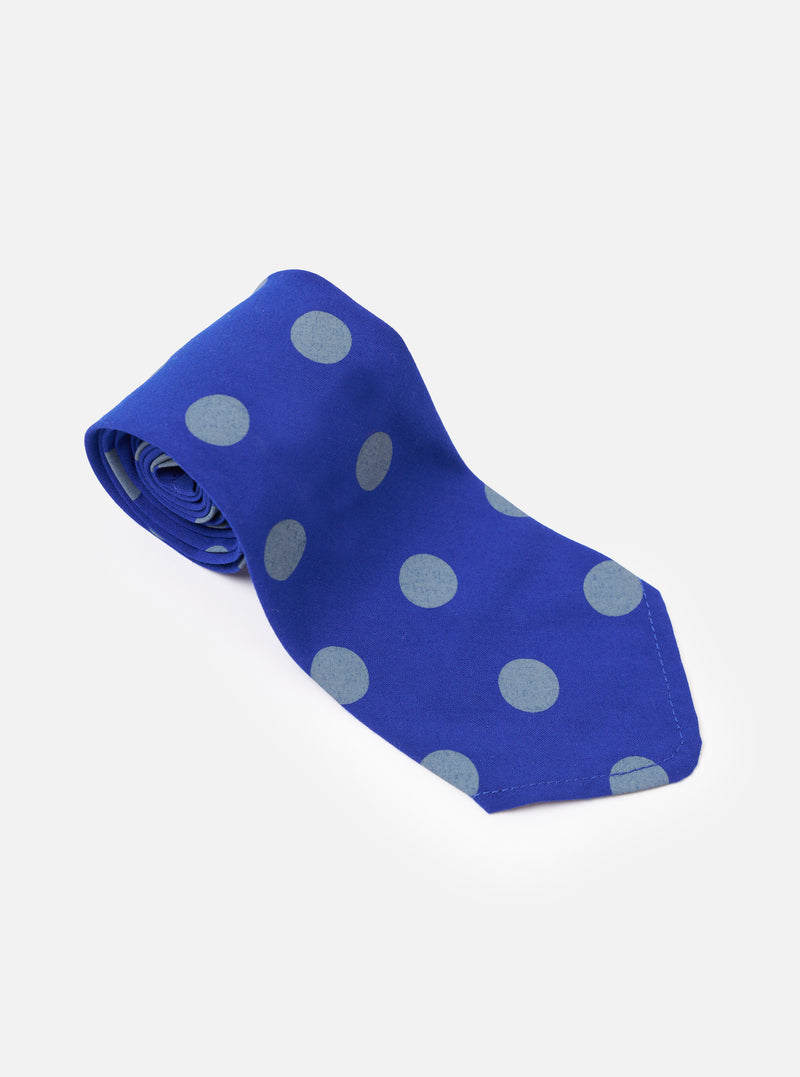 The Blue Bold Dot Print Rayon Tie is shown from the back as a flat lay against a plain white background. The image highlights the clean construction of the tie's reverse side, including the keeper loop and the smooth finish of the blue rayon fabric with its white polka dot print.