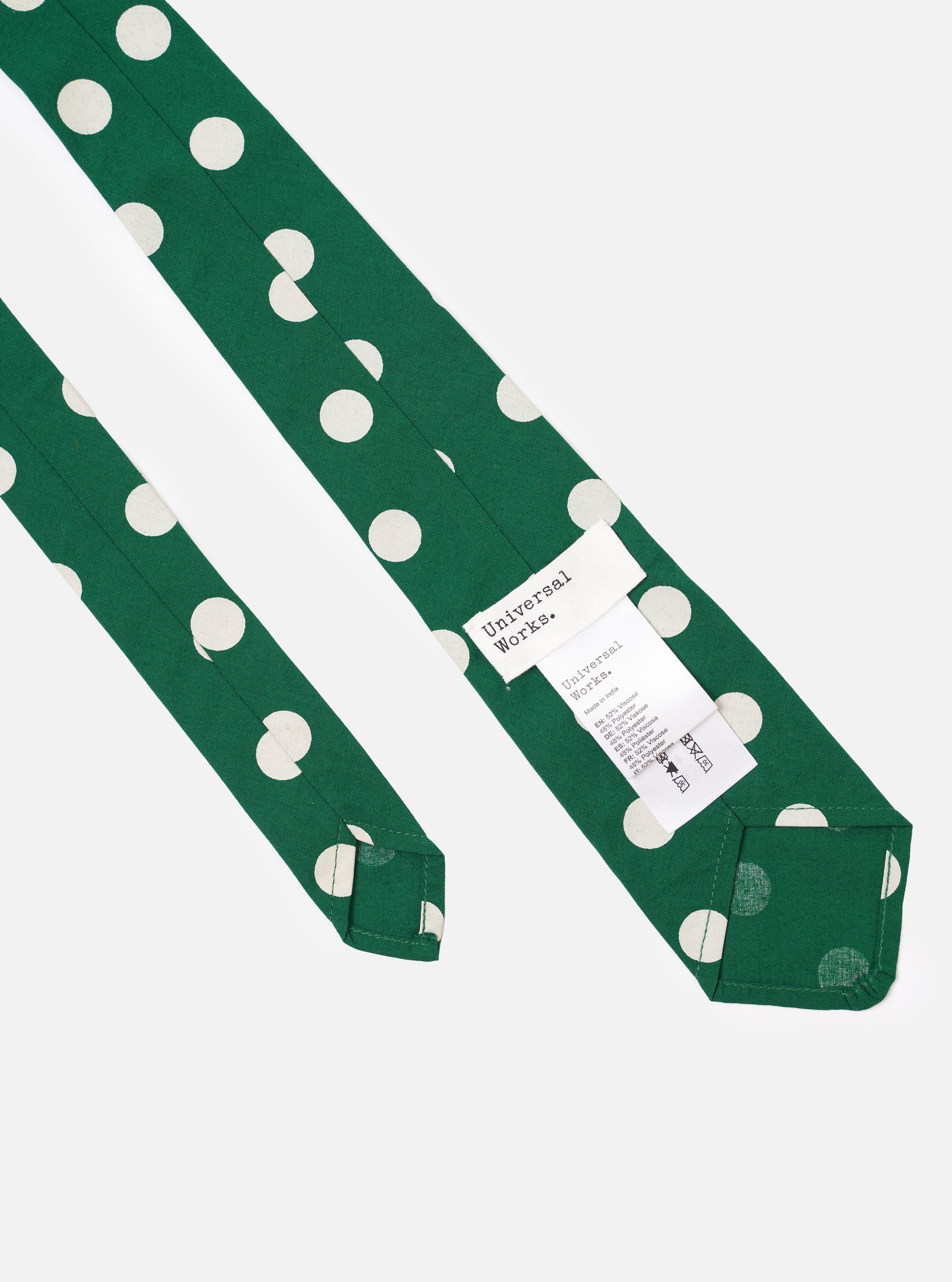 The Forest Green Bold Dot Print Rayon Tie is shown in a close-up detail shot as a flat lay against a plain white background. The image focuses on the central part of the tie, highlighting the intricate bold dot pattern and the smooth texture of the forest green rayon fabric.