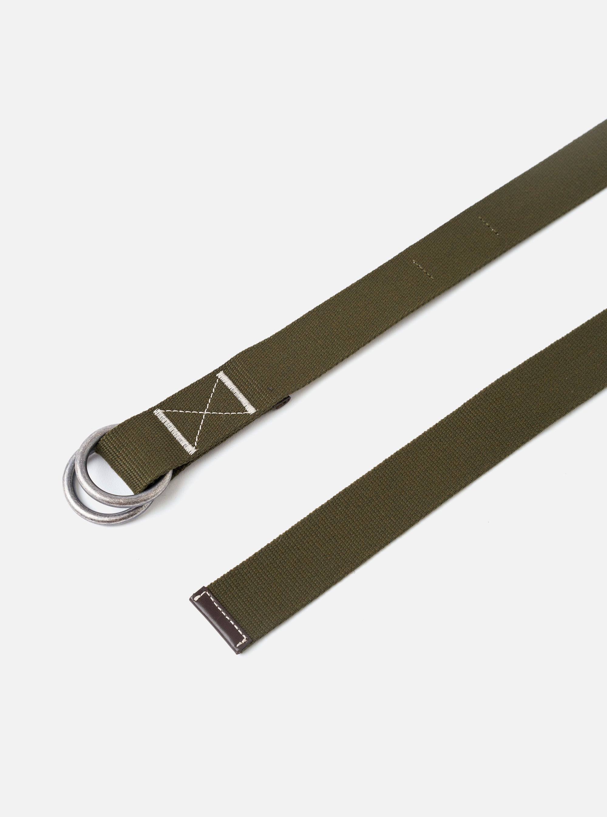 The Olive Canvas Webbing O Ring Belt is displayed as a flat lay against a plain white background. The belt features a textured olive green canvas webbing construction with visible contrast stitching and a double metal O-ring buckle for an adjustable closure.