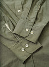 Close-up flat-lay detail of the olive chambray Daybrook shirt, showing two barrel cuffs each fastened with two white four-hole buttons with gold stitching. The placket is visible at the top with a single button. Fine topstitching runs along the cuff edges. The woven chambray fabric has a subtle two-tone texture.