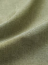 Close-up of the olive green chambray fabric of the Daybrook Shirt, showing a plain weave texture with a subtle two-tone yarn construction. A folded seam runs diagonally across the frame, highlighting the fabric weight and finish.