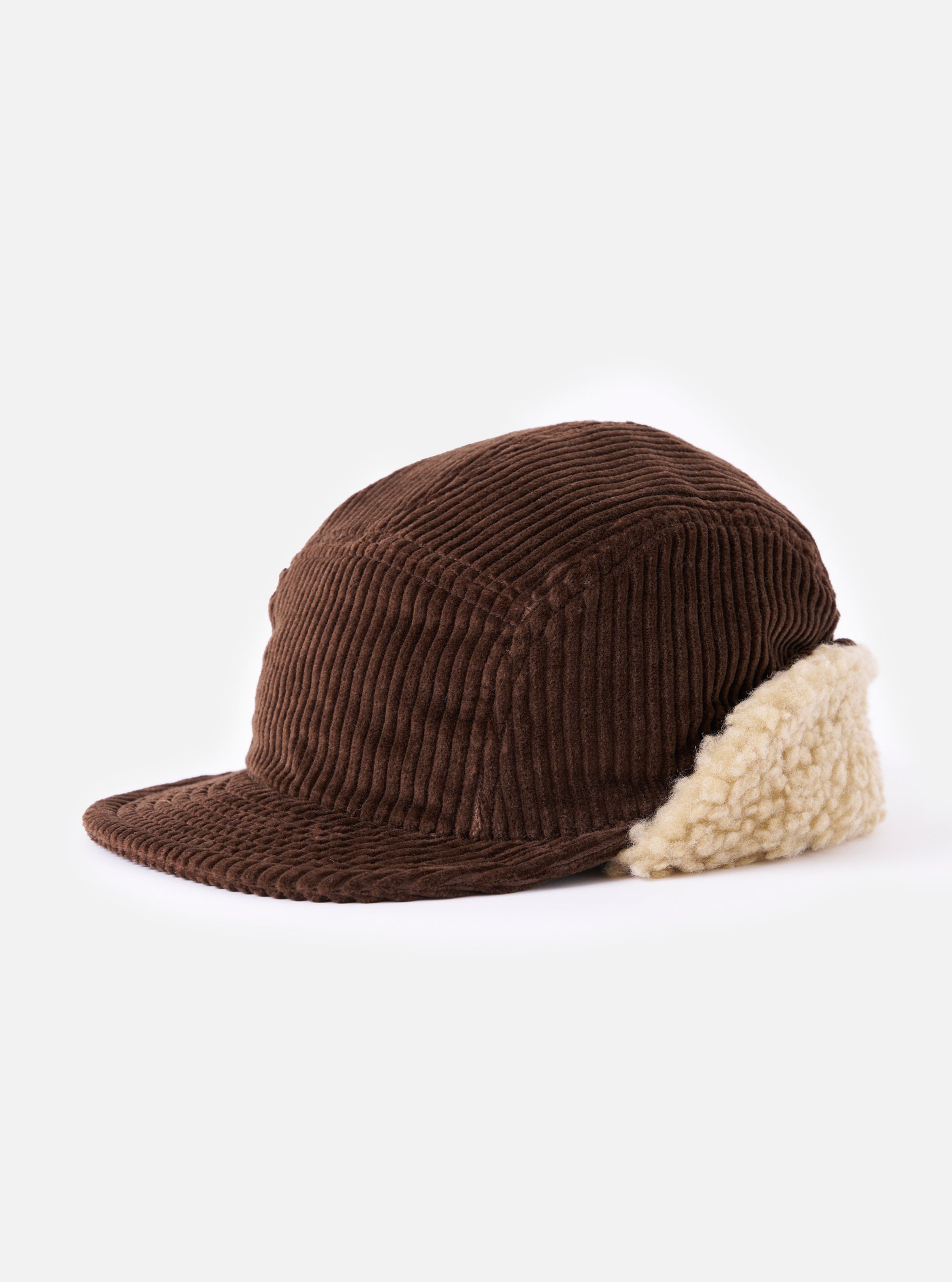 Side view of a cableami® Brown Corduroy 5w Cap on a white surface. The cap is brown corduroy with cream-colored ear flaps. The background is plain white.
