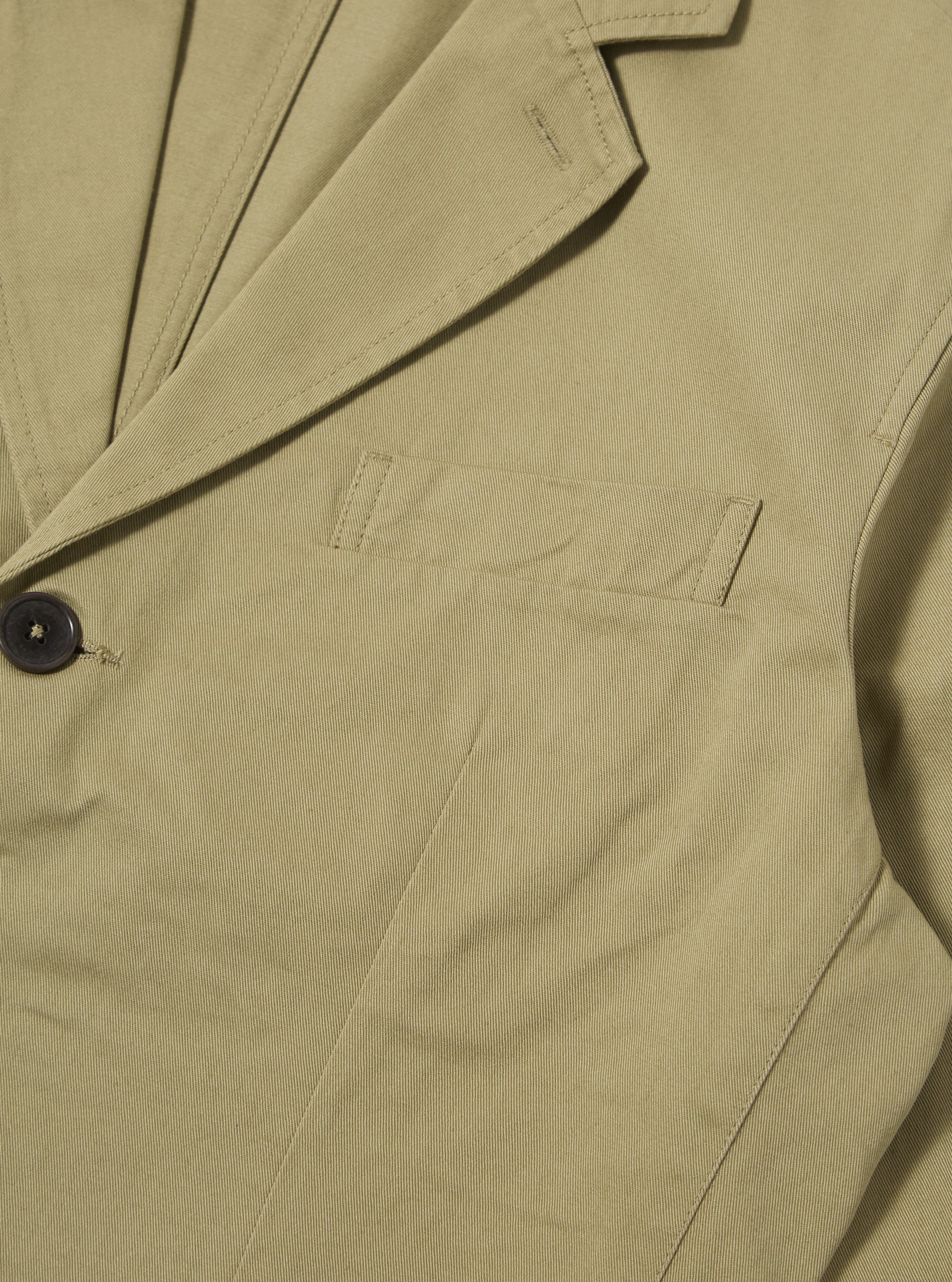 Close-up of the sand twill London Jacket, showcasing its fine twill texture, tailored fit, and dark button. The jacket is displayed on a flat surface.