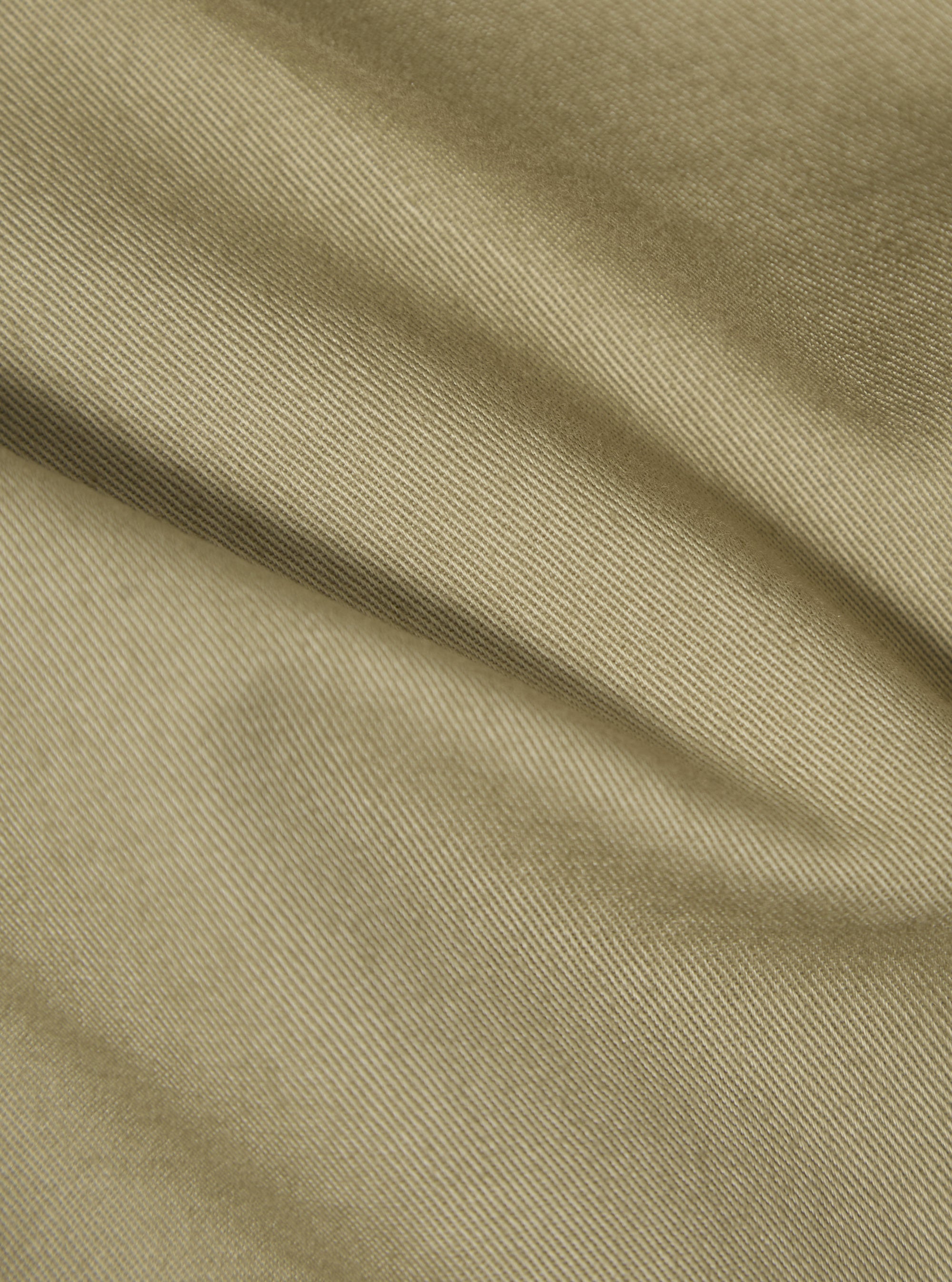 Close-up of the sand twill fabric of the London Jacket, showing the texture and color. The material is draped to highlight its quality.