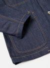 Close-up of the Indigo 13oz Selvedge Denim Bakers Jacket on a white surface. Shows the jacket's indigo denim, gold stitching, and pocket detail.