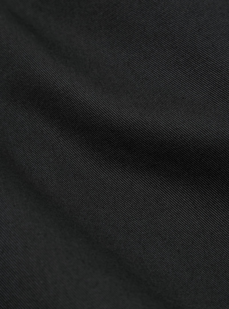 Close up on the black twill fabric of the London Jacket. The material has a subtle diagonal weave pattern.