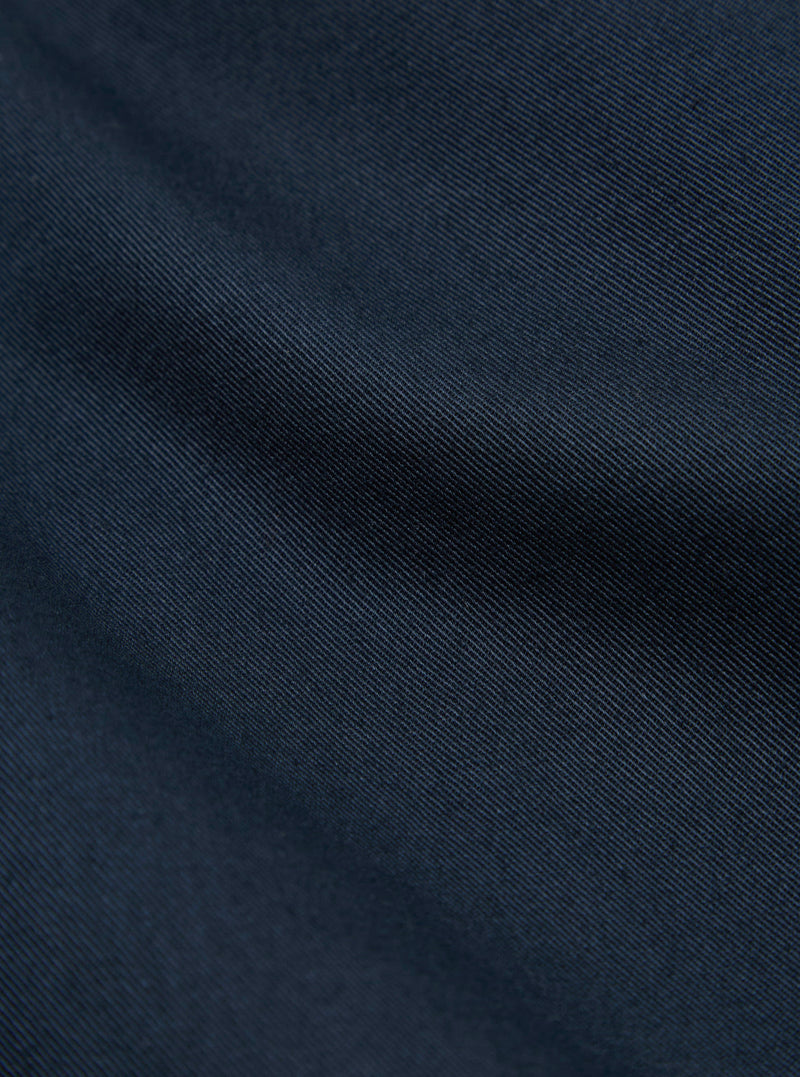 Close-up of the navy twill fabric of the Kyoto Work Jacket, showing the texture and color in detail. The background is a plain surface.