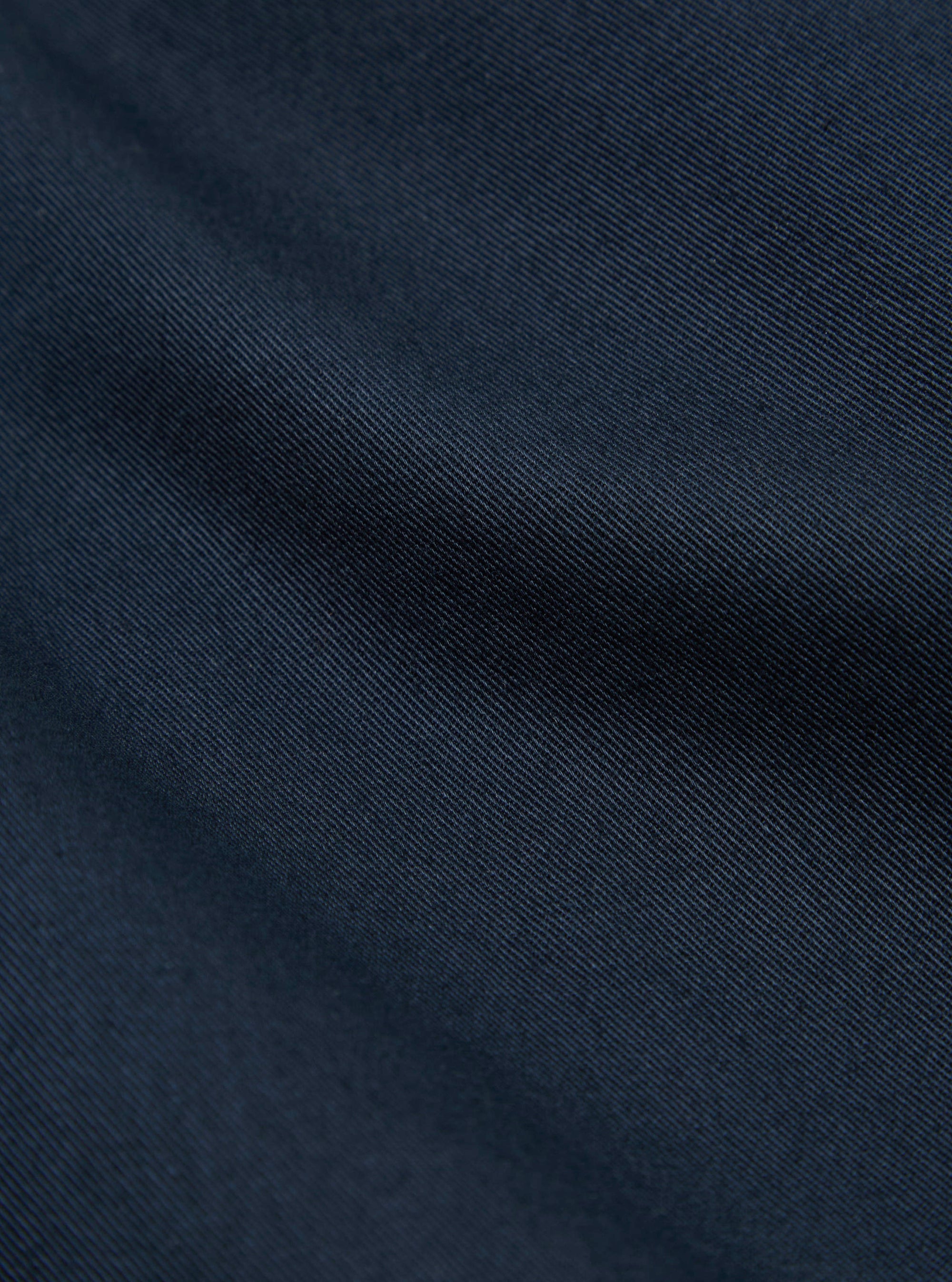 Close-up of the navy twill fabric of the Kyoto Work Jacket, showing the texture and color in detail. The background is a plain surface.