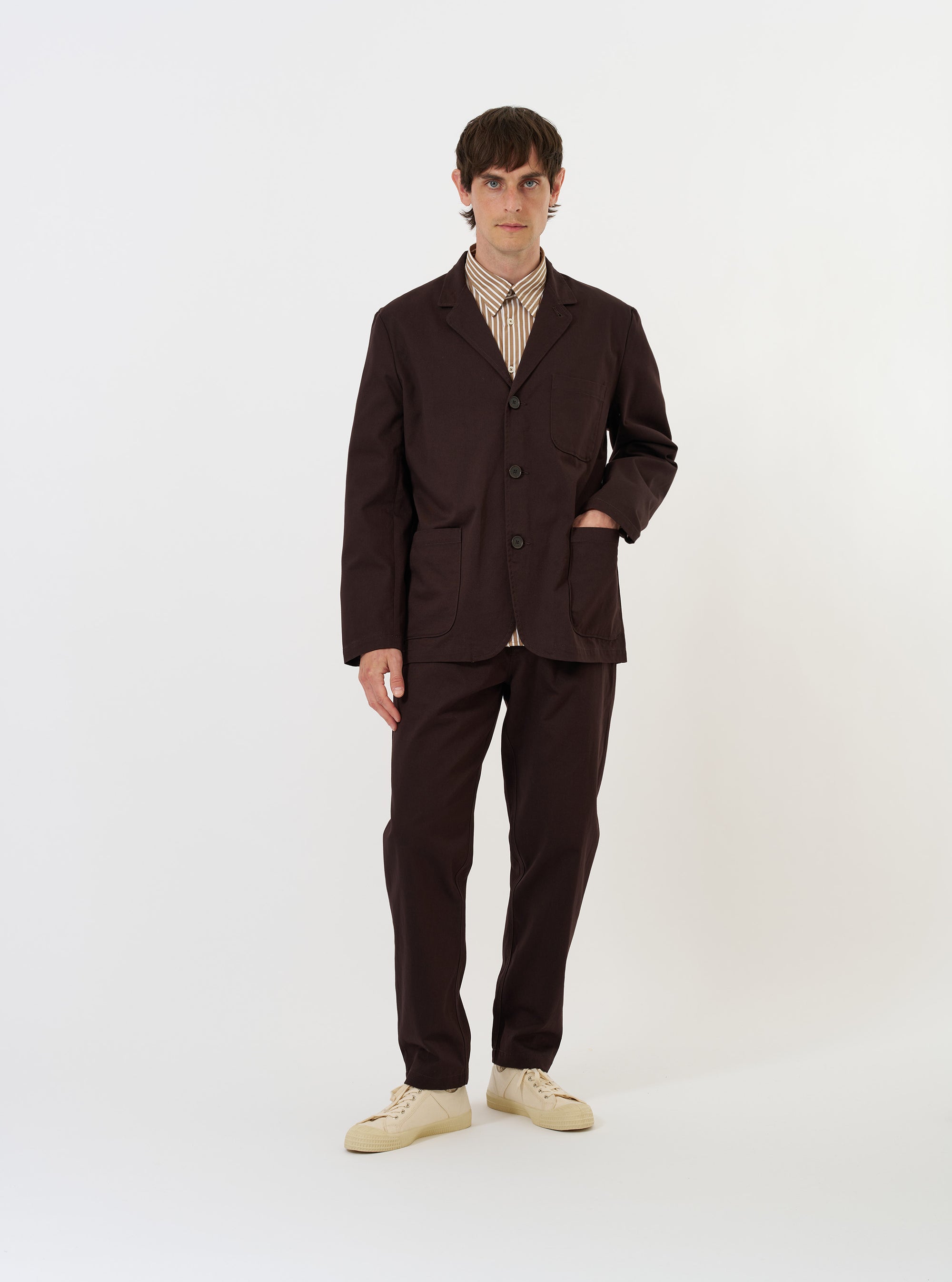 The Brown Twill Three Button Jacket is shown laid flat against a plain white background. This unstructured, single-breasted jacket features a notched lapel, a three-button front closure, and three prominent patch pockets—one on the chest and two larger ones at the waist.