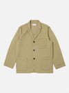 The Sand Twill Three Button Jacket is laid flat on a white background. The jacket is a light tan color and made of twill. It has three dark buttons and two large pockets.