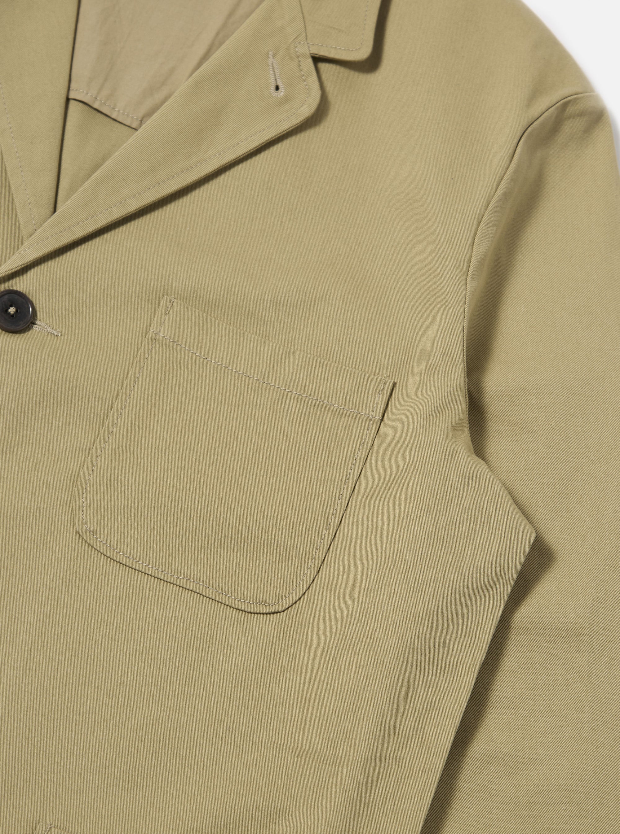 Close-up of the sand twill three button jacket on a white background. The jacket has a pocket and dark button.