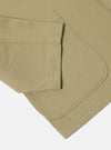 Close-up of the sand twill three button jacket showing the sleeve and rounded edge of the jacket on a white background.