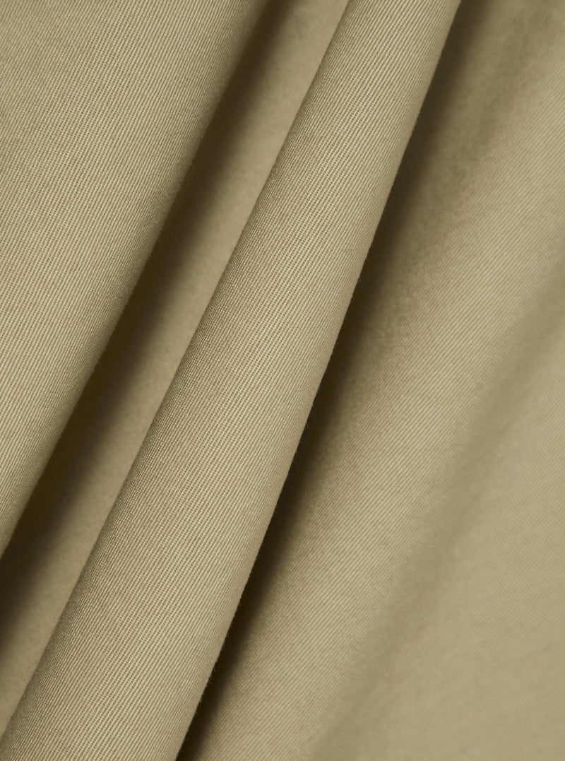 Close-up of the sand twill fabric of the Kyoto Work Jacket, showing the texture and color. The material is draped to highlight its quality.