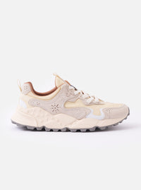 The Flower Mountain Milk/Light Beige Suede/Nylon Rulis Uni is shown as a flat lay against a plain white background. The sneaker features a technical nylon upper with overlapping light beige suede panels and a contrasting white rubber sole with a textured, indented tread. The design includes cream-colored cotton laces, reinforced eyelets, and a webbing pull tab at the heel.