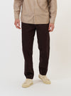 A model is wearing the Brown Twill Military Chino against a plain white background. The brown trousers feature a straight leg and are shown from the waist down, paired with dark footwear. The image highlights the fit and the durable cotton twill fabric of the chinos.