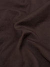 A close-up fabric swatch of the Brown Twill Pleated Track Pant shows a detailed view of the brown cotton twill material. The image highlights the diagonal weave and textured surface of the fabric.