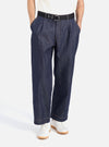 A model poses in the Indigo 13oz Selvedge Denim Duke Pant. The dark wash denim pants are styled with a black belt and white sneakers against a clean white background.